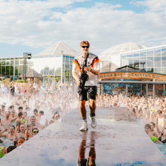 An artist performs on stage in front of an audience in a pool