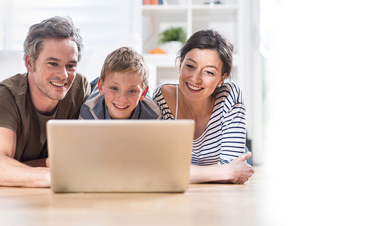 A family with father, mother and child sit in front of the laptop and look at the screen.
