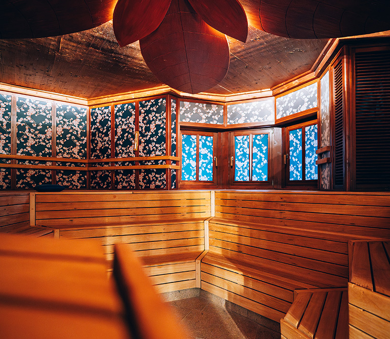 Sauna room with wooden benches and walls featuring a cherry blossom pattern at Therme Erding