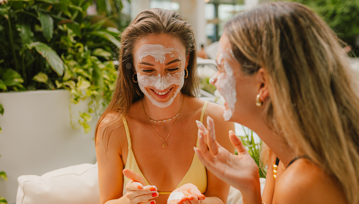Zwei Frauen tragen sich eine Gesichtsmaske auf.