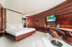 Moderne Yacht-Kabine im Hotel Victory der Therme Erding mit elegantem Holzwanddesign, großem Bett, Flachbildfernseher und Schreibtisch