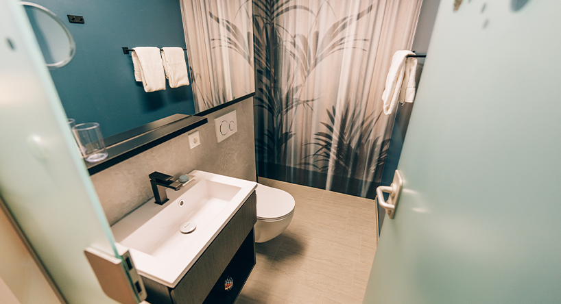 Bathroom with grey wallpaper, view of large mirror, toilet and washbasin