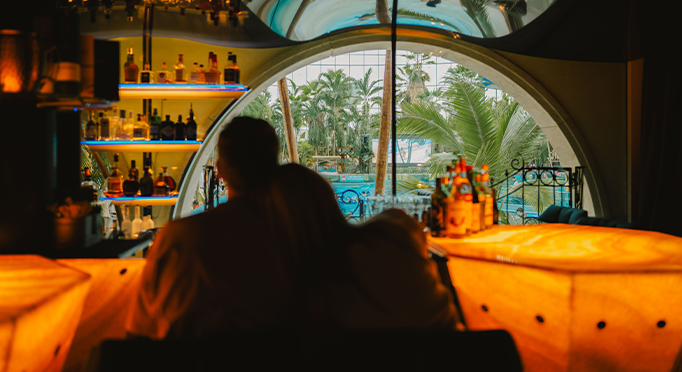 Pärchen sitzt an Bar und blickt auf das Wellenbad