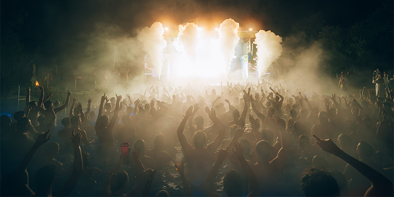 Menschenmenge in einem Schwimmbad bei einem Event mit hellen Lichtern und Nebel auf der Bühne