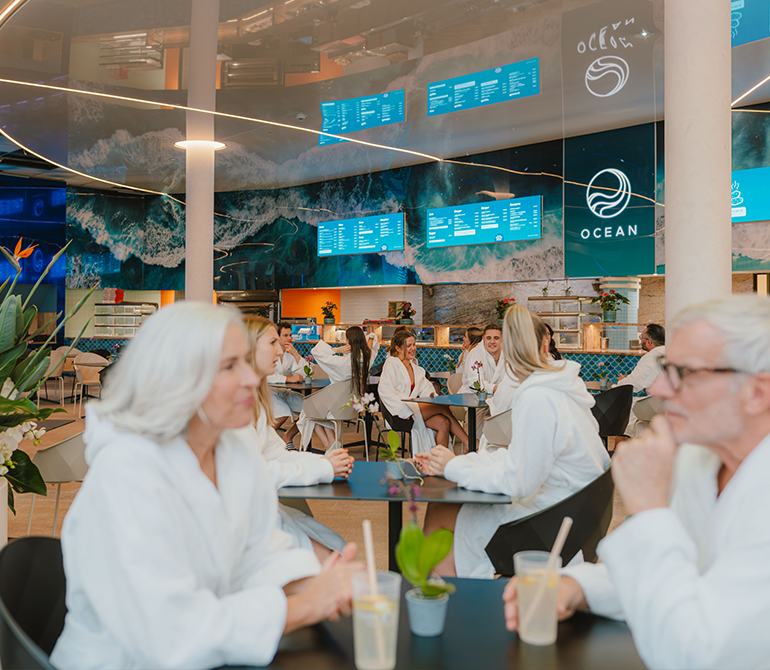 Mehrere Gäste sitzen mit Bademänteln bekleidet im Ocean Restaurant der Therme.