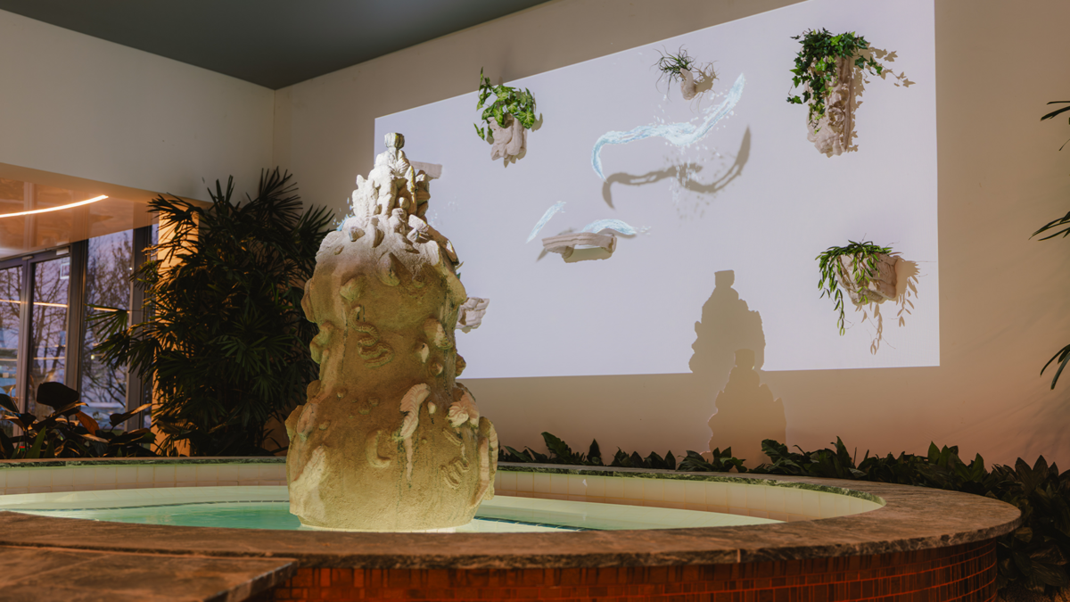 Animierte Wasserstrahlen gleiten spielerisch zwischen skulpturalen Elementen und Pflanzen hinter dem Jungbrunnen hin und her.