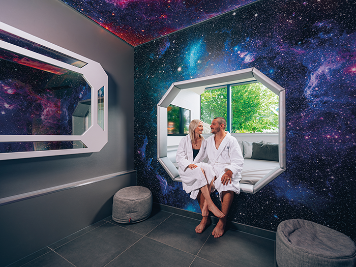 A couple is sitting in a lounge designed in a space-themed style.