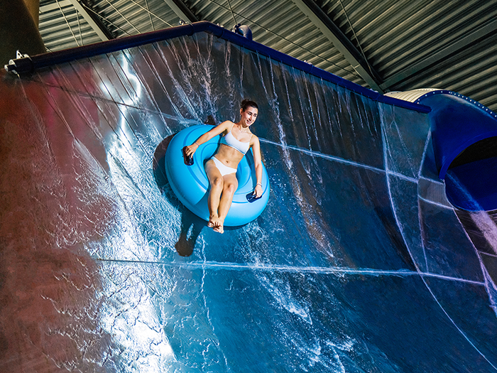 A woman slides down a large halfpipe water slide on a tire.