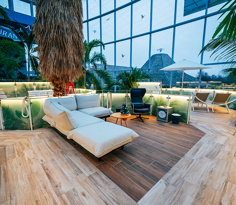 Lounge-Bereich mit einem Bürostuhl, einer Couch, Schirm und einem Kühlschrank.