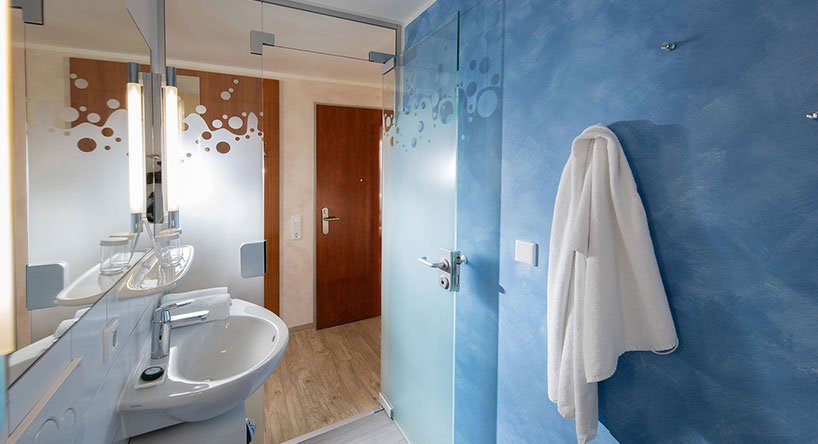 Victory Gästehaus Therme Erding Studio Bad Bathroom with washbasin, mirror and blue wallpaper