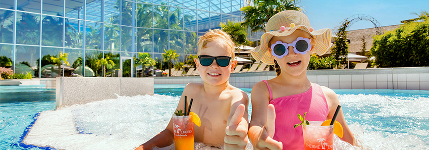 Zwei Kinder sind im Crazy River und trinken einen Kindercocktail.
