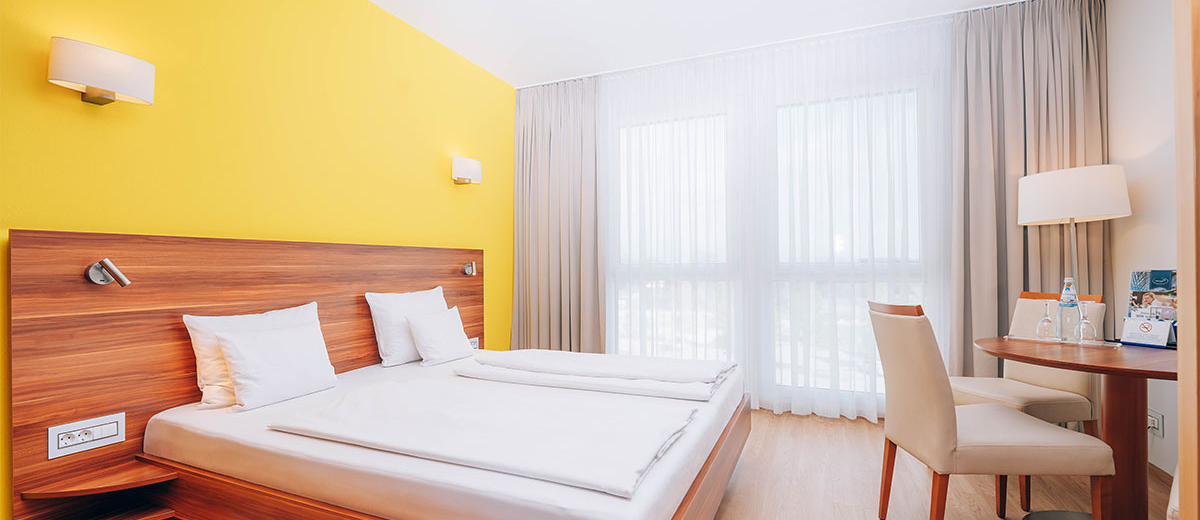 Bright hotel room with double bed, table and chairs