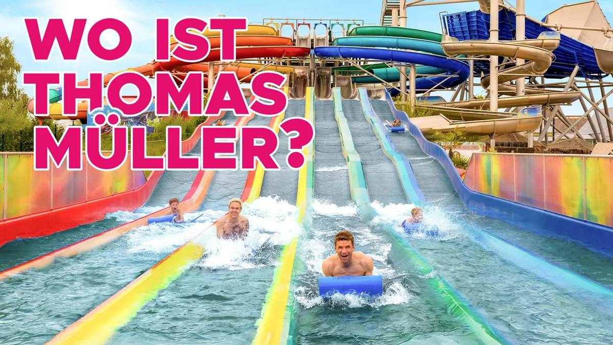 Mehrere Personen rutschen auf bunten Wasserrutschen im Therme Erding, Text 'Wo ist Thomas Müller?' in großen pinken Buchstaben