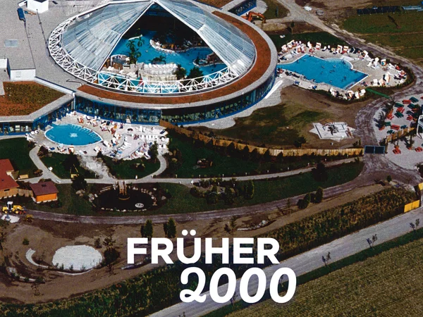 Luftaufnahme der Therme Erding mit Rutschen und Pools, parkähnlich gestaltet. Text: "Früher 2000". Früher vs. heute.